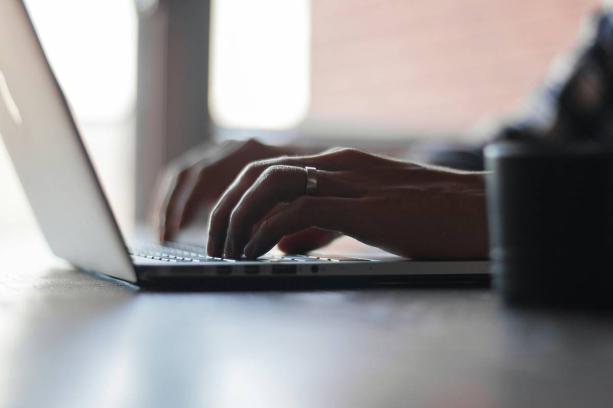 Professional writing email at desk with world map background illustrating email etiquettes in communication